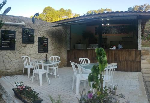 a patio with white chairs and a table and a restaurant at Pousada Vale da Serra in Serra Negra