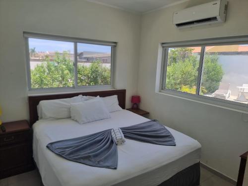 a bed in a bedroom with two windows at Ocean Breeze Apartments in Aruba in Oranjestad