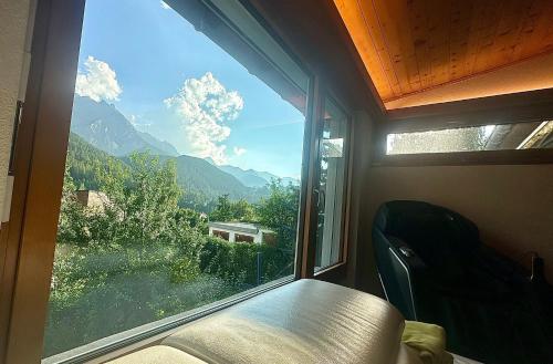 a window in a room with a view of a mountain at Chasa Stefania, modernes Engadiner Haus mit Wellness und Sauna in Scuol