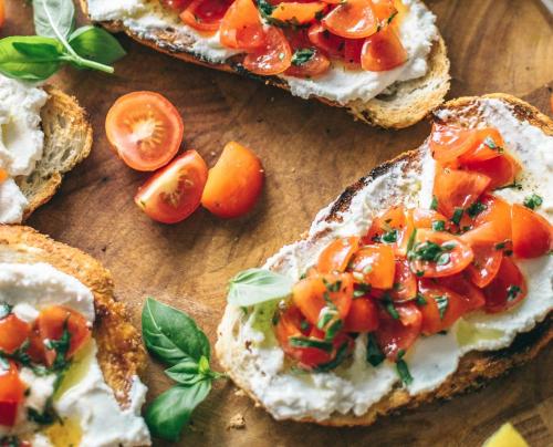 a group of sandwiches with tomatoes on a wooden cutting board at Crowne Plaza Melbourne Carlton by IHG in Melbourne