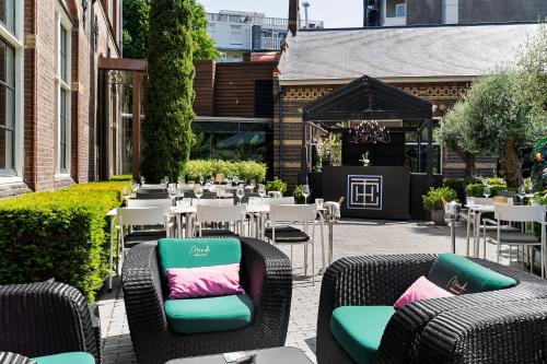 a patio with wicker chairs and tables and a tent at The College Hotel Amsterdam, Autograph Collection in Amsterdam