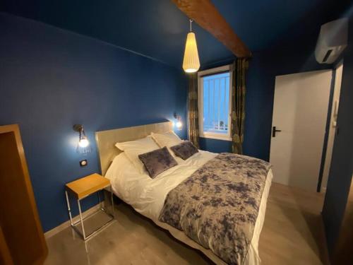 une chambre avec un grand lit avec un mur bleu dans l'établissement T2 douillet rénové hyper centre, à Nîmes