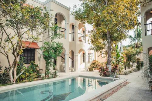 a swimming pool in front of a building with trees at Casa Valladolid Boutique Hotel in Valladolid