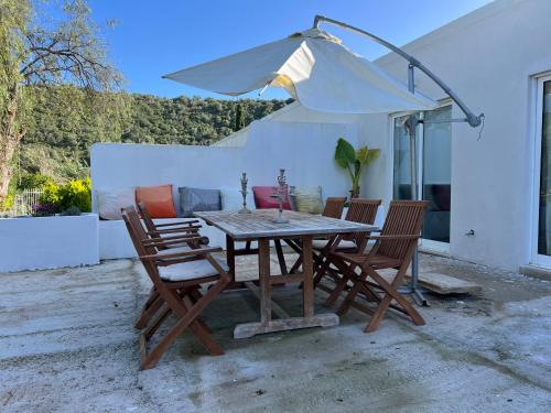 a wooden table with chairs and an umbrella at Casa Lourenço in Silves