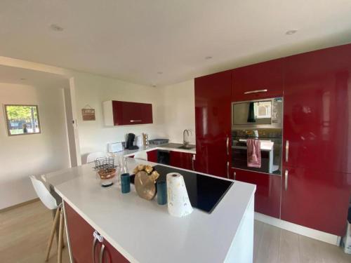 une cuisine avec des armoires rouges et un comptoir blanc dans l'établissement Appartement coquet avec 3 chambres en face des pistes de ski, à Gérardmer
