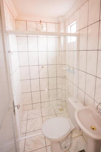 a white bathroom with a toilet and a sink at Hotel Diniz in Barra do Corda