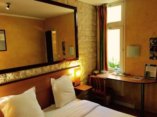a bedroom with a bed and a mirror and a desk at Hôtel Bosquet Pau Centre - Self Check In Budget Hotel in Pau