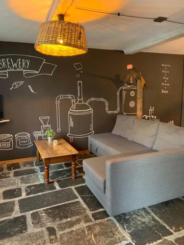ein Wohnzimmer mit einem Sofa und einer Wand mit Zeichnungen darauf in der Unterkunft Les gîtes de la Brasserie d'Aubrives La Malterie et la Houblonnière in Aubrives
