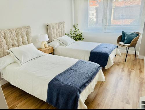 a bedroom with two beds and a chair at Piso Porta do Sol in Ribeira
