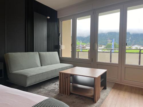 a living room with a couch and a table and windows at TITLIS Alpine Studio - close to cable car - nahe der Gondel in Engelberg