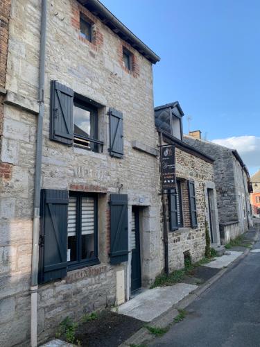 ein altes Backsteingebäude mit schwarzen Rollläden auf einer Straße in der Unterkunft Les gîtes de la Brasserie d'Aubrives La Malterie et la Houblonnière in Aubrives