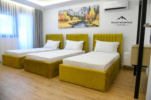 two beds in a room with a painting on the wall at BlackMountain Hotel in Kolgecaj