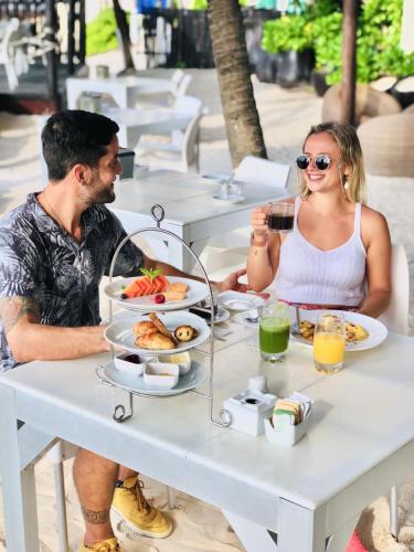 プラヤ・デル・カルメンにあるエル タージ オーシャンフロント&ビーチサイド コンド ホテルの食べ物を持ってテーブルに座っている男性と女性