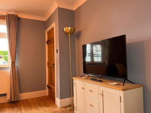 a living room with a flat screen tv on a cabinet at One Jubilee Cottages in Shugborough