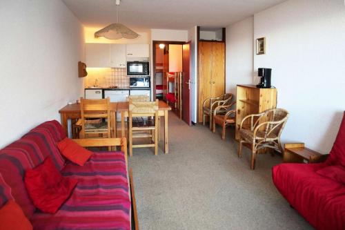 un salon avec un canapé rouge et une table dans l'établissement Résidence Le Cairn - STUDIO N° 0507 LE CAIRN MAE-4531, aux Orres