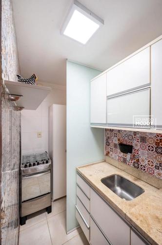 a small kitchen with a sink and a refrigerator at Moderno 1 Quarto Dentro da Vila in Praia do Forte