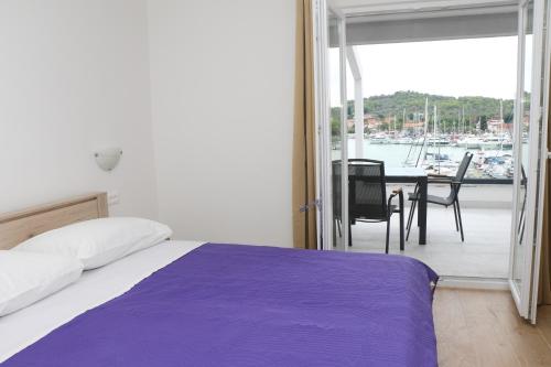 a bedroom with a bed and a balcony with a boat at Apartmani Mary S2 in Kukljica