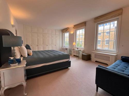 a bedroom with a bed and a couch and windows at Charming 3 Bed Luxury Flat in Central London in London