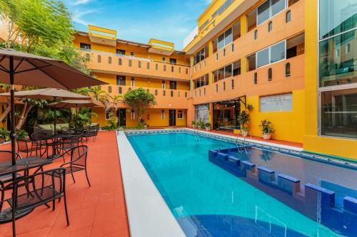 a pool in front of a hotel with tables and chairs at Hotel Plaza Mirador, Ciudad del Carmen in Ciudad del Carmen
