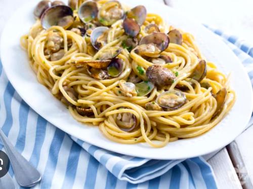 a plate of pasta with oysters and mushrooms on a table at Villa KAMBUSA in Las Galeras