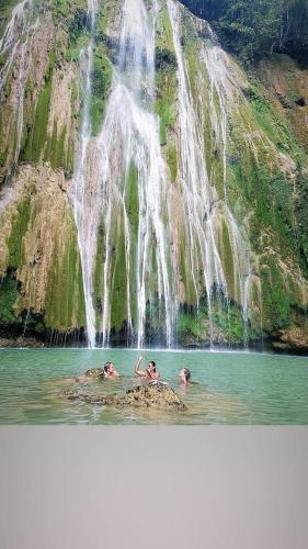 three people in the water in front of a waterfall at Villa KAMBUSA in Las Galeras