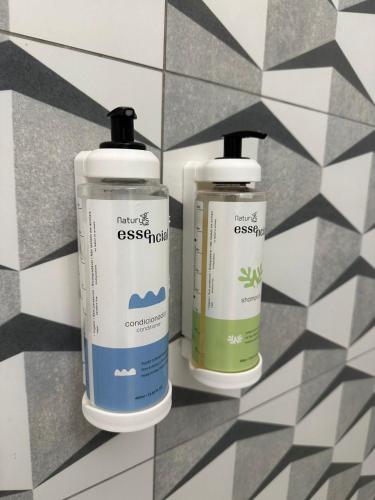 two bottles of disinfectants sitting on a tile wall at Kitnet em Americana SP in Americana