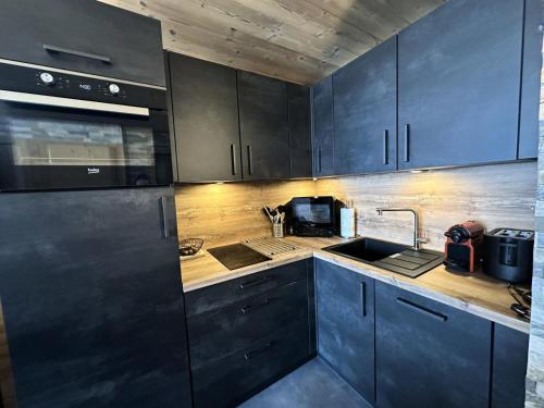 - une cuisine avec des armoires bleu foncé et un évier dans l'établissement Résidence L'albane - L'ALBANE - pied de pistes avec accès PISCINE - MAE-1331, à Vars