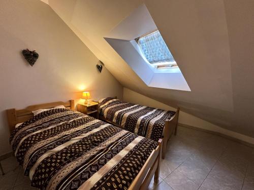 - 2 lits dans une chambre avec une lucarne dans l'établissement Résidence L'eterlou - L'ETERLOU MAE-2071, à Vars