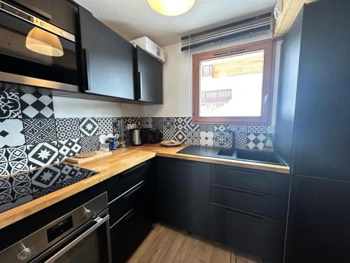 une cuisine avec des armoires noires et une fenêtre dans l'établissement Résidence Le Bouquetin Ii - LE BOUQUETIN II MAE-9961, à Vars