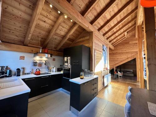 a kitchen with black cabinets and a wooden ceiling at Chalet Mountainside - CHALET MOUNTAIN SIDE Tout inclus Classé 4 MAE-9971 in Vars