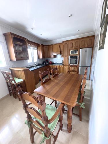 a kitchen with a wooden table and wooden chairs at Nice House next to Sotogrande Port and Marina in Torreguadiaro