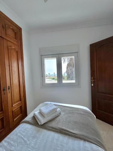 a white bedroom with a bed with two towels on it at Nice House next to Sotogrande Port and Marina in Torreguadiaro