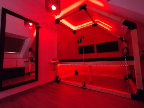 une chambre rouge avec un miroir et des lumières rouges dans l'établissement Le Royaume des Sens, à Sainte-Opportune-du-Bosc