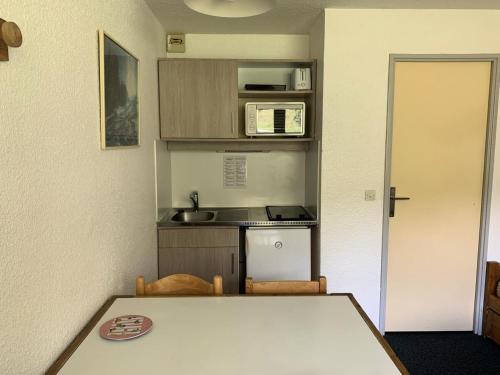 une petite cuisine avec une table et un micro-ondes dans l'établissement Résidence Median - Studio pour 3 Personnes MAE-1651, aux Menuires