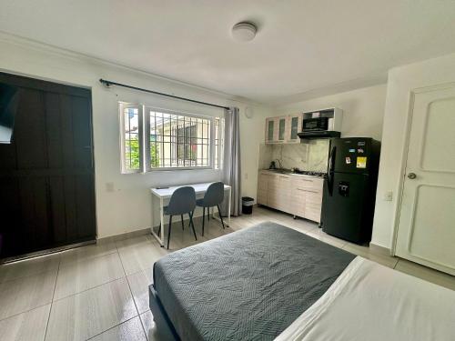 a bedroom with a bed and a table and a kitchen at Apartahotel Poblado-Aguacatala in Envigado