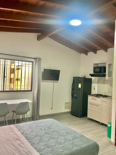 a room with a bed and a kitchen with a refrigerator at Apartahotel Poblado-Aguacatala in Envigado