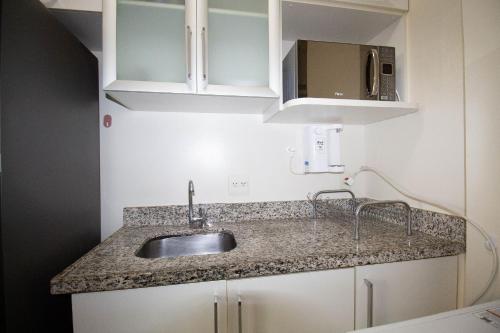 eine Küchentheke mit Spüle und Mikrowelle in der Unterkunft OZPED Flats Particulares Edifício Premier in Brasilia