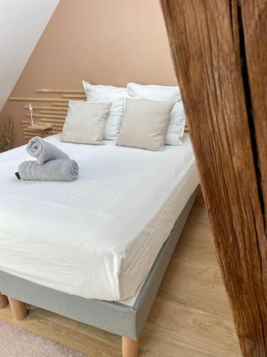 - un lit avec des oreillers blancs et un animal rembourré dans l'établissement INTO THE WINE, à Dijon