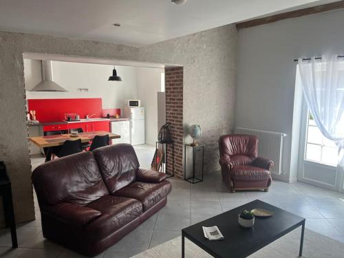 un salon avec un canapé en cuir et une table dans l'établissement Maison au calme, à Baccon