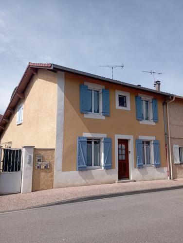 une maison avec des fenêtres bleues et une porte rouge dans l'établissement Gite le Port, à Loyettes