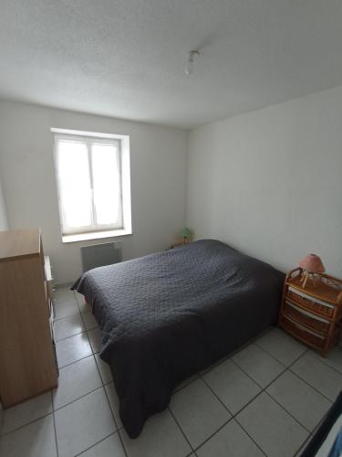 une chambre avec un lit noir et une fenêtre dans l'établissement Gite le Port, à Loyettes