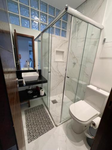 a bathroom with a shower and a toilet and a sink at Condomínio Wembley Tenis Praia Das Toninhas J406 in Ubatuba