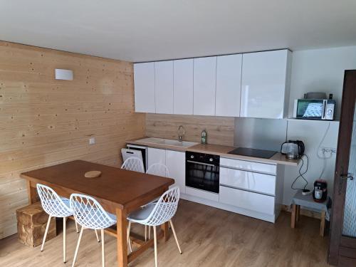 une cuisine avec des armoires blanches et une table et des chaises en bois dans l'établissement T3 avec vue montagne, aux Contamines-Montjoie