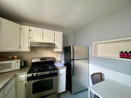 a kitchen with white cabinets and a stove and refrigerator at Clover 2900 - Apartment and Rooms with Private Bathroom near Washington Ave South Philly in Philadelphia