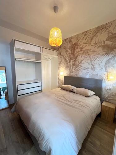 une chambre avec un grand lit et un lustre dans l'établissement Le Raffiné LOUSTAL-OC TARBES PYRÉNÉES, à Tarbes