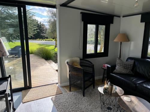 a living room with a couch and a sliding glass door at Adorable little container house in Hastings