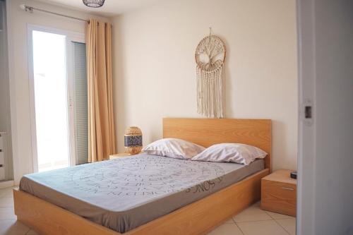 a bedroom with a bed with a wooden headboard and a window at 2 bdr cozy beachside apartment, Copacabana - LCGR in Mindelo