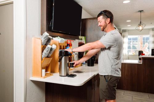 a man standing in a kitchen with a coffee pot at The Windstar Hotel - Carolina Beach in Carolina Beach