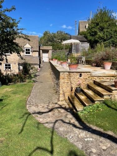 a stone wall with a bench in a yard at Masons Cottage, an Idyllic retreat in an area of outstanding beauty, close to Blenheim Palace, Oxford & The Cotswolds in Stonesfield