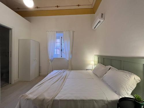 a bedroom with a large white bed with a window at Casa Rosetta appartamenti in Porto Torres